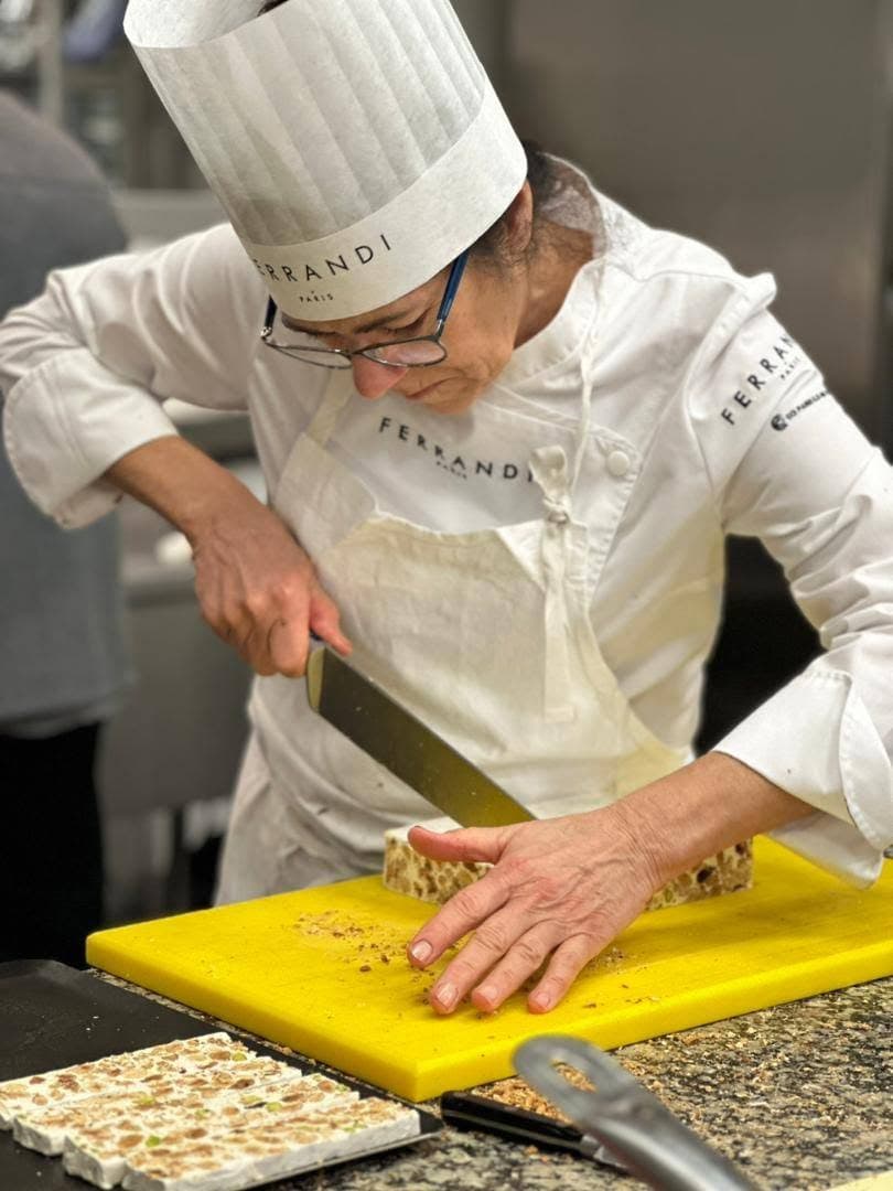 Christina in chef's whites at FERRANDI Paris, slicing handmade nougat